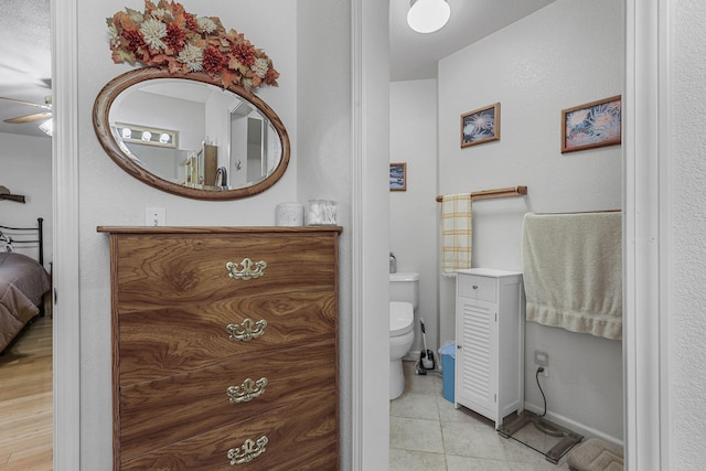 bathroom with connected bathroom, baseboards, ceiling fan, toilet, and tile patterned floors