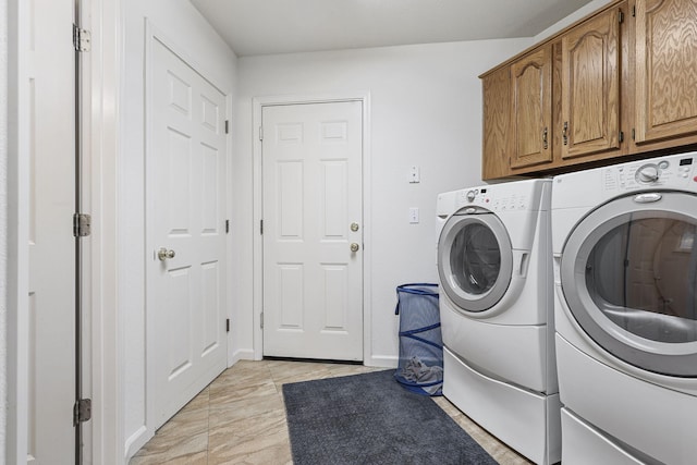 washroom featuring cabinet space, baseboards, and washer and clothes dryer