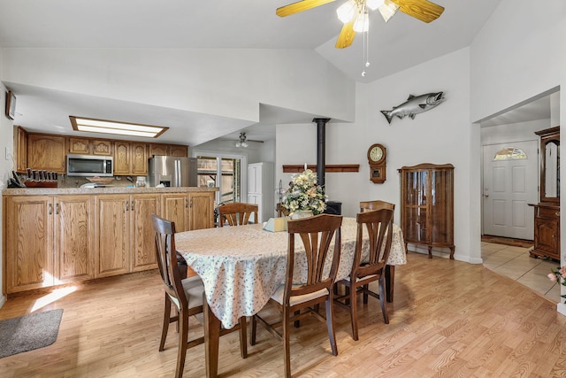dining room featuring a ceiling fan, light wood-type flooring, and high vaulted ceiling