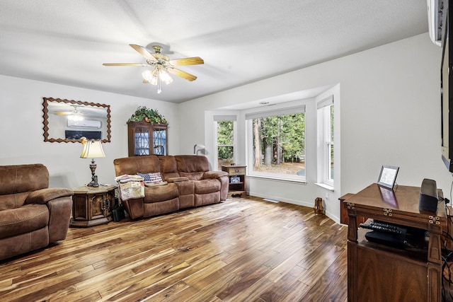 living room featuring a textured ceiling, wood finished floors, baseboards, and ceiling fan