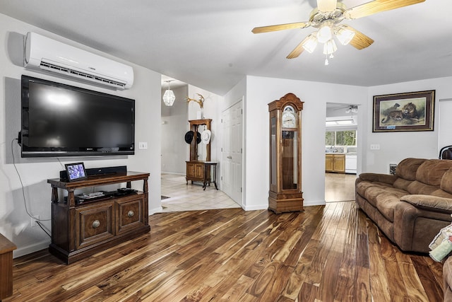 living room with baseboards, a wall mounted AC, a ceiling fan, and wood finished floors