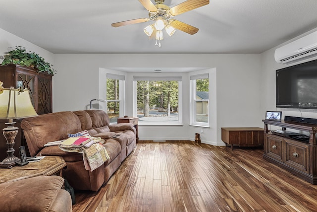 living area featuring baseboards, a wall mounted AC, a ceiling fan, and wood finished floors