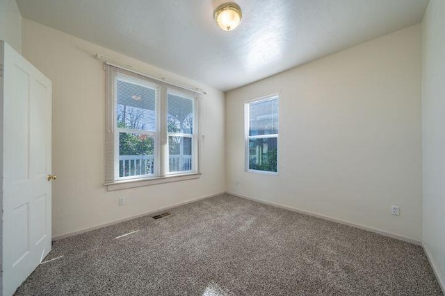 carpeted spare room with visible vents and baseboards