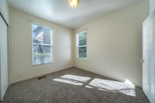 carpeted spare room featuring visible vents and baseboards