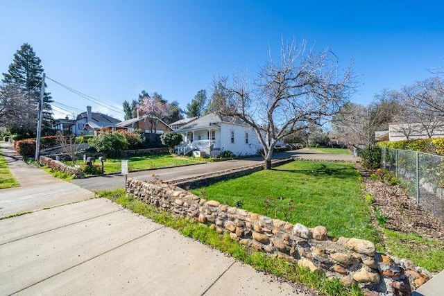 view of side of home with a yard, fence, and driveway