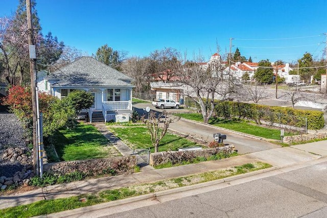 exterior space with a fenced front yard, covered porch, driveway, and a front lawn