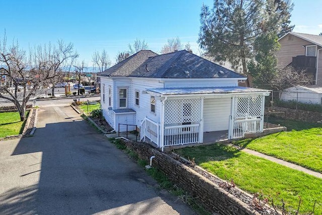 view of front facade with roof with shingles and a front yard