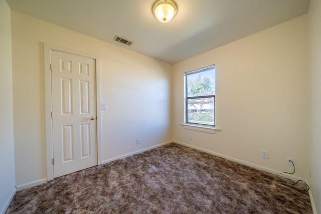 carpeted spare room featuring visible vents and baseboards