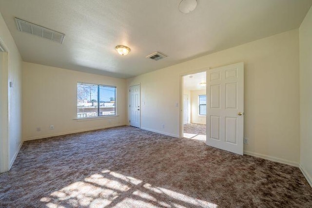 carpeted spare room featuring visible vents and baseboards