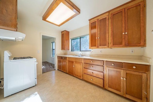 kitchen with brown cabinets, a sink, ventilation hood, light countertops, and range