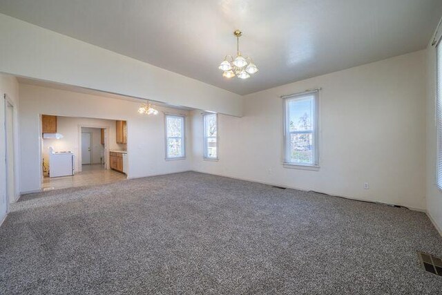 spare room featuring a notable chandelier, visible vents, and light carpet