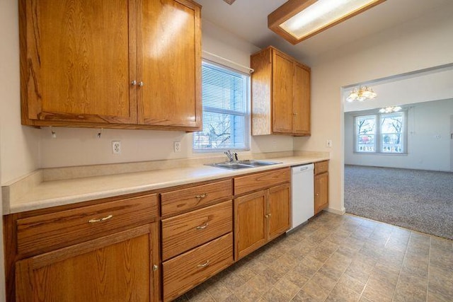 kitchen with brown cabinetry, a sink, light countertops, dishwasher, and light colored carpet