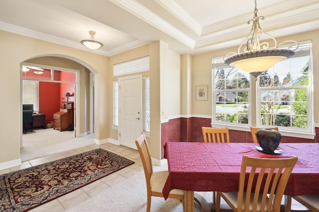 dining space featuring arched walkways, tile patterned flooring, baseboards, and ornamental molding