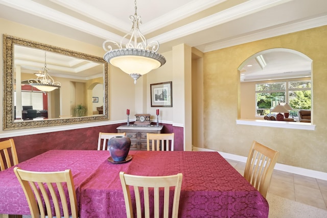 dining space with tile patterned floors, baseboards, a tray ceiling, ornamental molding, and arched walkways