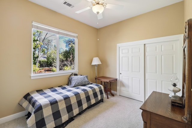 bedroom with visible vents, baseboards, ceiling fan, a closet, and light colored carpet