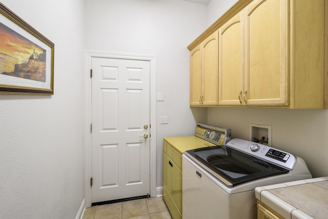 clothes washing area with washer and dryer, baseboards, cabinet space, and light tile patterned floors