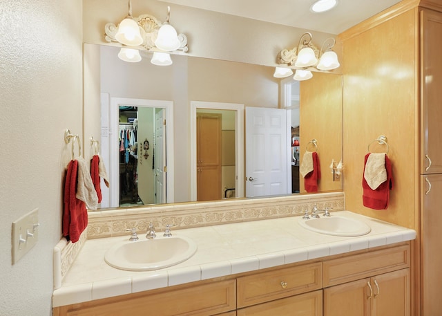 full bath featuring double vanity, a spacious closet, and a sink