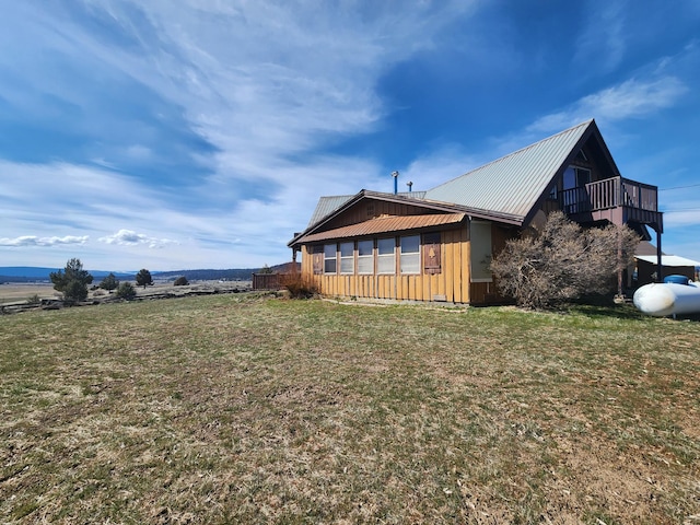 view of property exterior with a yard, board and batten siding, metal roof, and a balcony