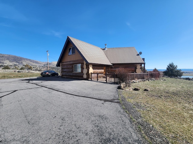 view of home's exterior featuring log siding, a garage, metal roof, and fence