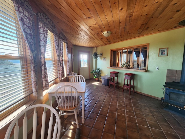 dining room with baseboards, wood ceiling, a wood stove, and tile patterned flooring