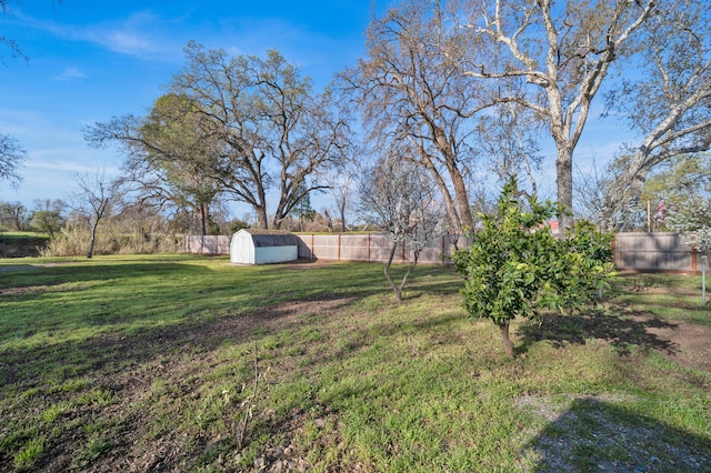 view of yard with a storage shed, an outbuilding, and fence