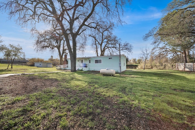 view of yard with an outbuilding, a storage shed, and fence