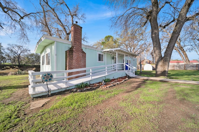 view of front of property featuring a front lawn, a chimney, and fence