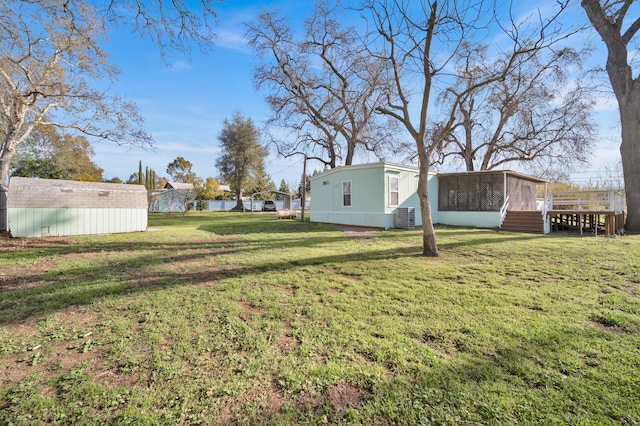 view of yard with a storage shed, an outbuilding, central AC unit, and a sunroom