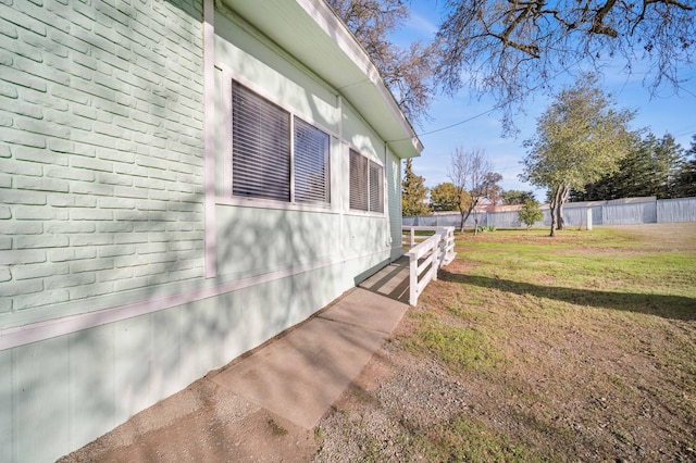 view of side of home featuring fence and a lawn