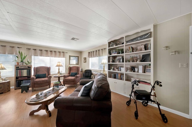 living room featuring wood finished floors, visible vents, and baseboards