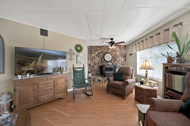 living room featuring visible vents, light wood-style floors, ceiling fan, and a wood stove