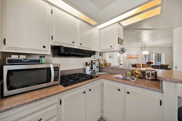 kitchen featuring under cabinet range hood, stainless steel microwave, white cabinetry, and black gas stovetop