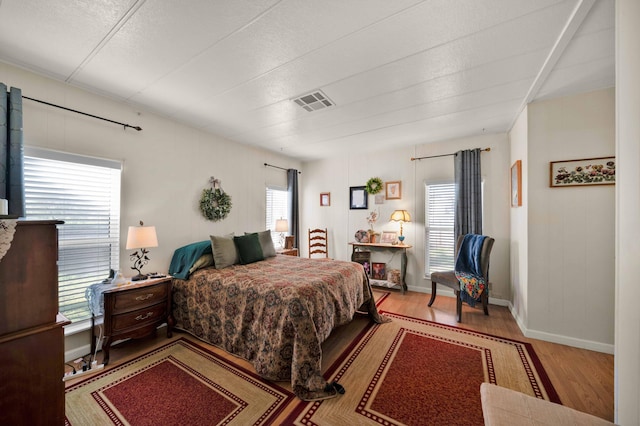 bedroom featuring visible vents, multiple windows, and wood finished floors