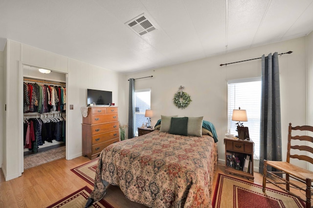 bedroom with light wood finished floors, visible vents, a spacious closet, and a closet