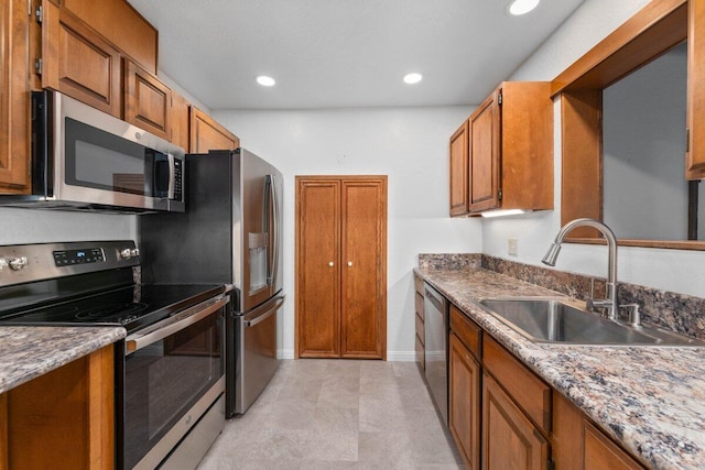 kitchen with brown cabinets, a sink, recessed lighting, appliances with stainless steel finishes, and baseboards