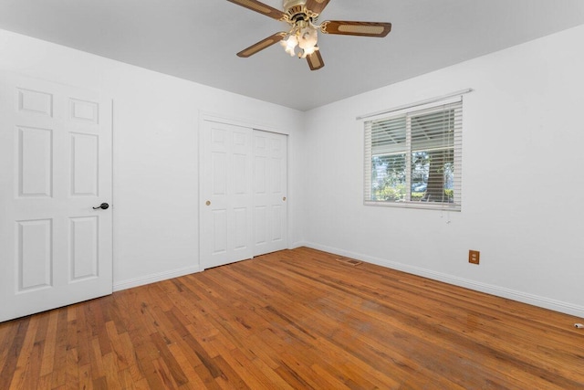 unfurnished bedroom with a ceiling fan, baseboards, visible vents, hardwood / wood-style flooring, and a closet