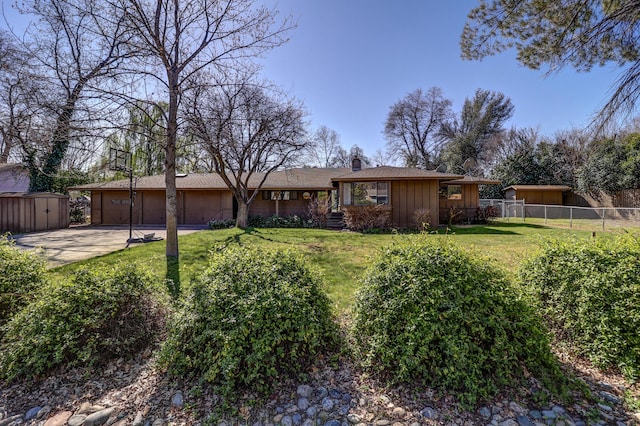 view of front facade with a front lawn, fence, a storage shed, board and batten siding, and concrete driveway