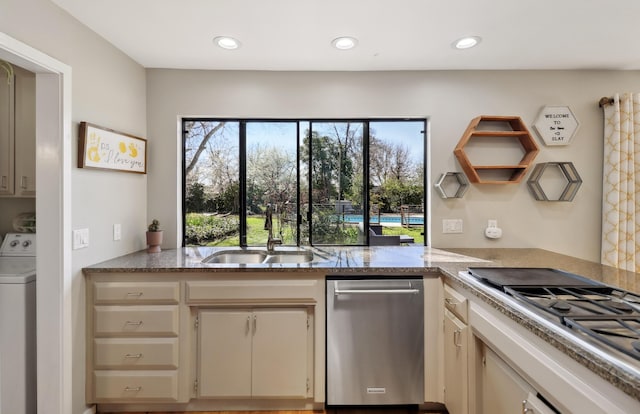 kitchen featuring a sink, light stone counters, recessed lighting, appliances with stainless steel finishes, and washer / dryer