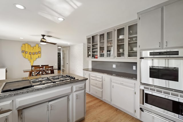 kitchen with recessed lighting, light wood-style floors, appliances with stainless steel finishes, glass insert cabinets, and ceiling fan