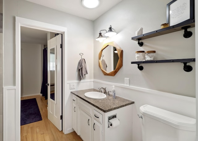 bathroom with toilet, vanity, and wood finished floors