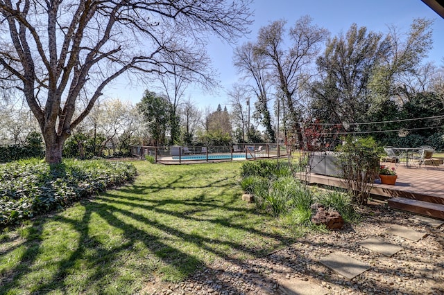 view of yard with a deck, a community pool, and fence