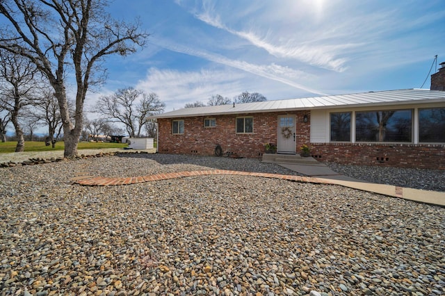 back of house with crawl space, brick siding, and a chimney