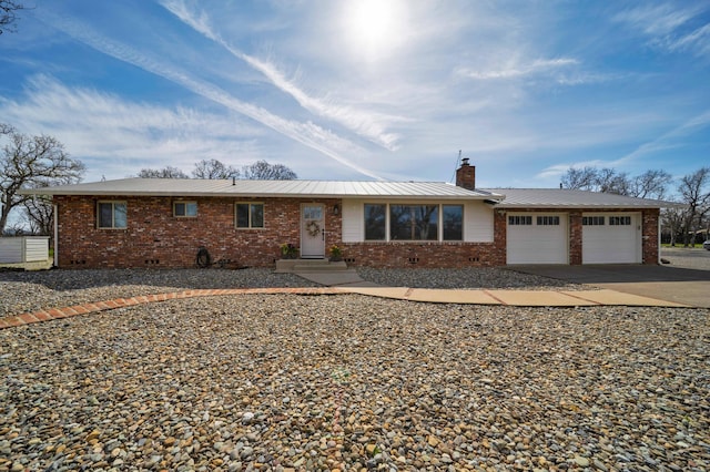 ranch-style home with a garage, brick siding, driveway, and a chimney