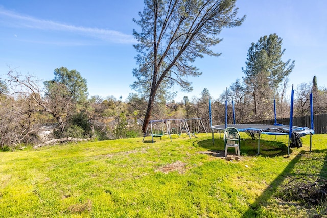 view of yard with a trampoline and fence