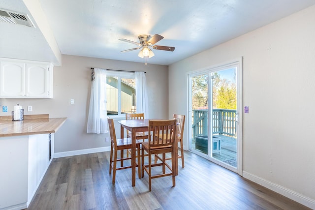 dining room with a ceiling fan, wood finished floors, visible vents, and baseboards