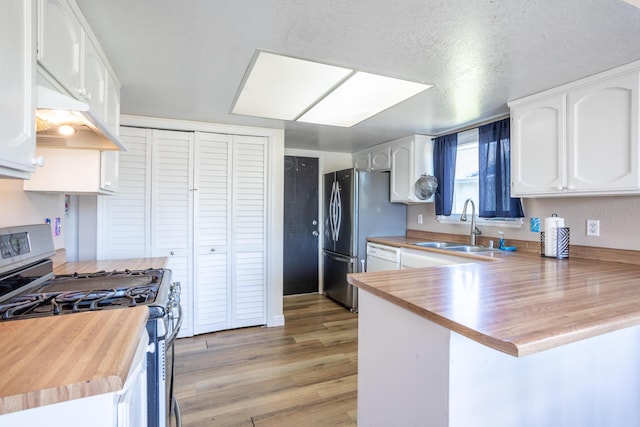 kitchen featuring light wood-style flooring, a sink, white cabinetry, appliances with stainless steel finishes, and a peninsula