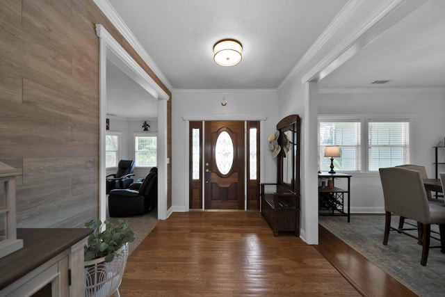 entryway featuring dark wood finished floors, crown molding, baseboards, and visible vents