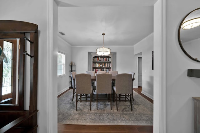 dining room with visible vents, baseboards, wood finished floors, and ornamental molding