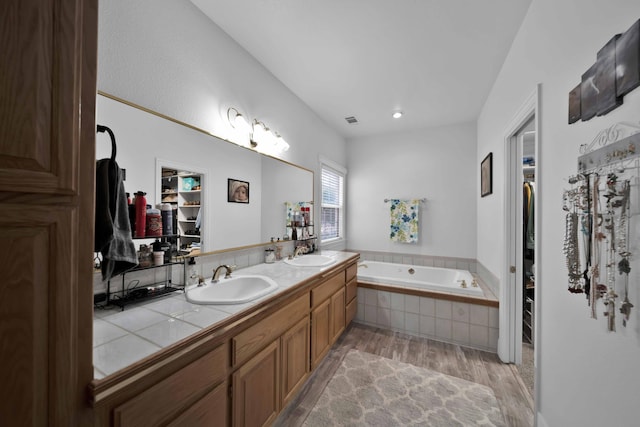 bathroom featuring a sink, wood finished floors, a bath, and double vanity