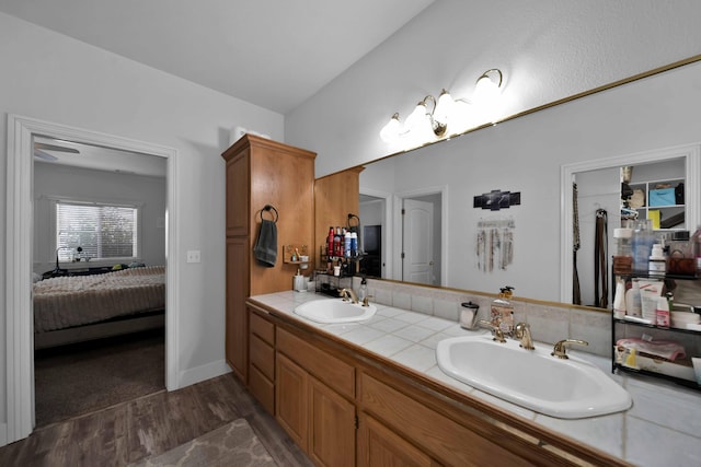 full bathroom featuring double vanity, connected bathroom, wood finished floors, and a sink